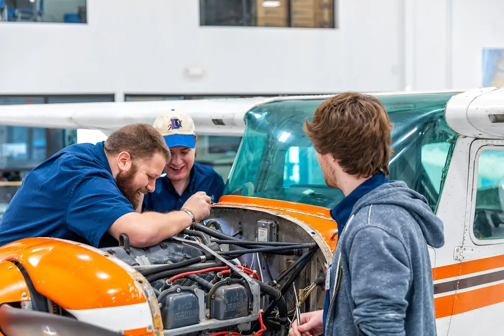Three kirkwood students working on the engine of a small plane.